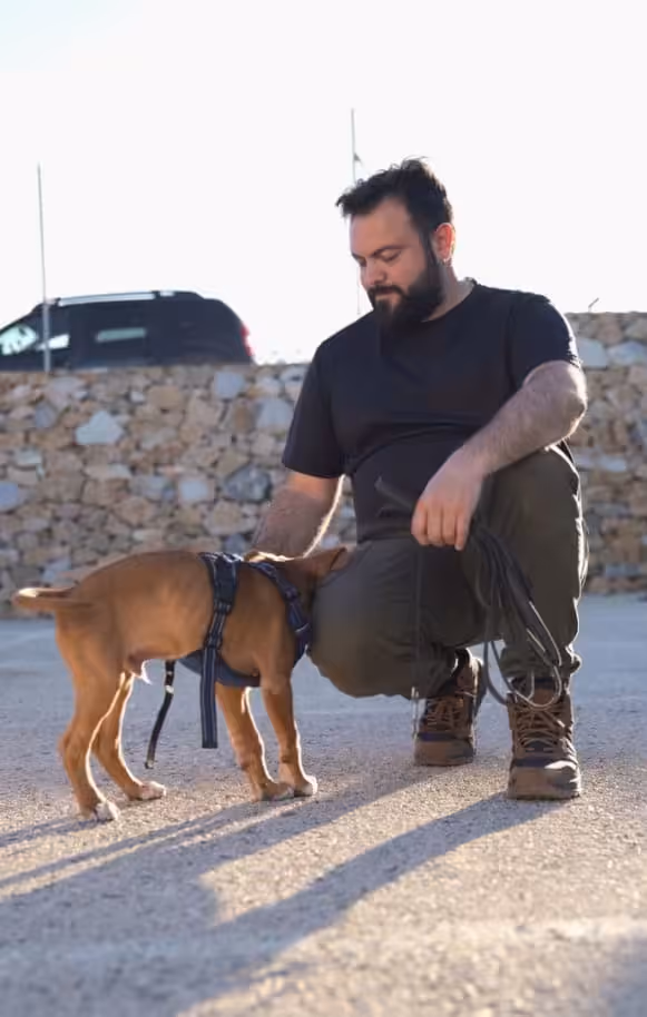 Pablo agachado acariciando suavemente a un perro marrón